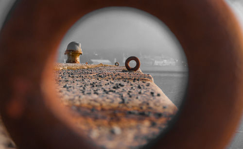 Close-up of rusty pier seen through circle shape metal