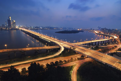 Aerial view of illuminated light trails on mapo bridge over han river against blue sky at night