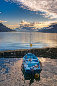 Boat moored on beach against sky during sunset