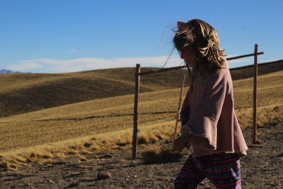 Rear view of girl standing on field against sky