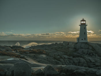 Lighthouse by sea against sky