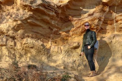 Low angle portrait of woman standing against rock formations