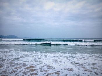 Scenic view of shore and sea against cloudy sky 