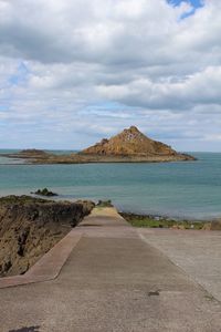 Empty road by sea against sky