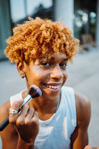 African american visagist holding brush and preparing makeup. looking at camera