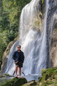 Rear view of man standing against waterfall