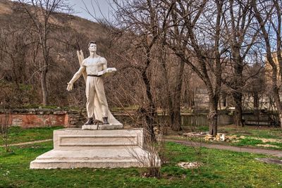 Statue against bare trees in cemetery