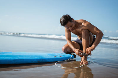 Rear view of shirtless man swimming in sea against sky