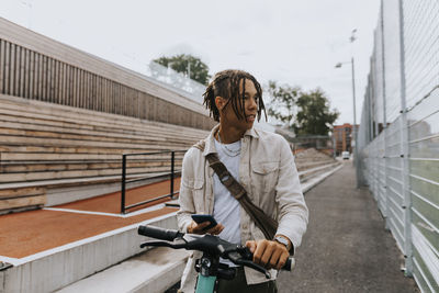 Teenage boy holding bicycle and looking away