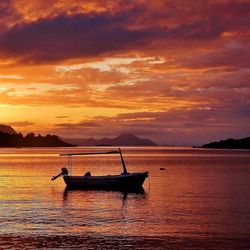 Silhouette boat in sea against orange sky