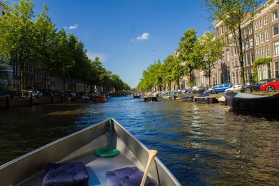 Boats moored on canal in city against sky