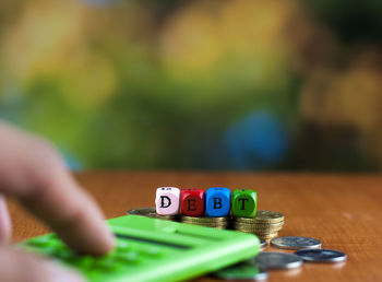 Close-up of person using calculator with coins on table