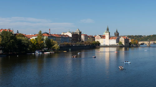 Buildings by river against clear sky