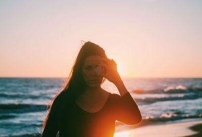 Portrait of woman on beach against sky during sunset