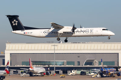 Airplane flying over airport runway against sky