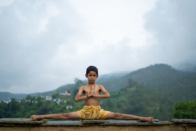 Portrait of man sitting on wood against sky