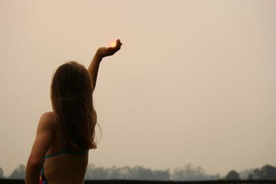 Rear view of woman standing against sky during sunset