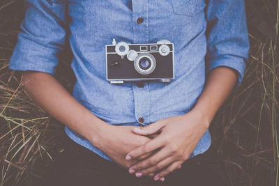 Midsection of woman with camera lying on field