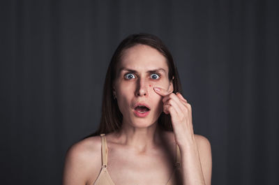 Portrait of worried young woman against black background