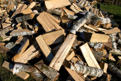 Pile and wall of cut birch wood and stacked wood logs ready for winter, standing on the grass