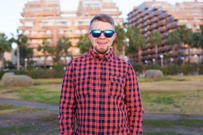 Portrait of young man wearing sunglasses while standing on road