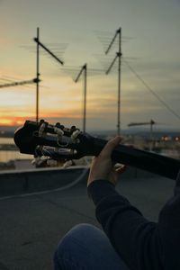 Close-up of man photographing against sky during sunset