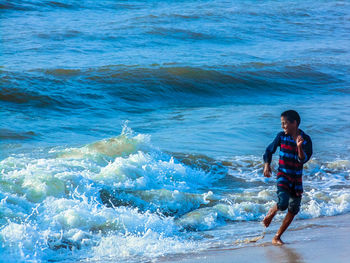 Full length portrait of happy man standing in sea