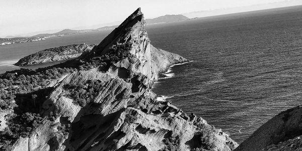 Panoramic view of rock formations in sea against sky