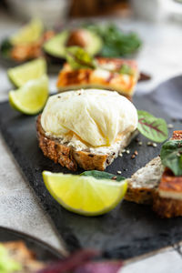 Variety of sandwiches with tartine bread with poached egg, avocado and cheese with salad and lime 