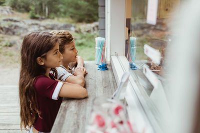 Side view of siblings standing by concession stand during vacation