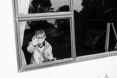 High angle view of boy wearing mask looking through window