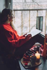 Woman sitting on table by window