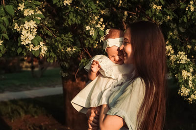 Portrait of young woman standing against trees