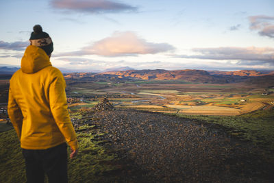 Rear view of man walking on road against sky during sunset