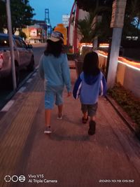 Rear view of people walking on street in city