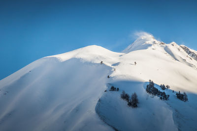 Scenic view of snow covered mountains against clear blue sky