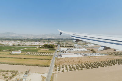 Airplane flying over agricultural landscape against clear sky