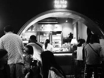 Rear view of people waiting at restaurant in city at night