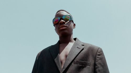 Portrait of young man wearing sunglasses against clear sky