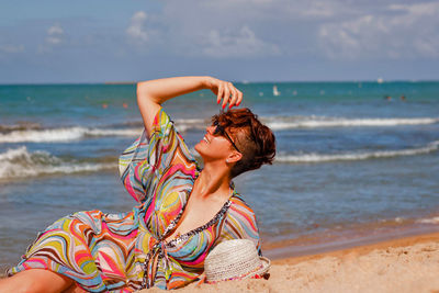 Close-up of woman lying down at beach against sky