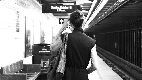 Rear view of woman standing at railroad station