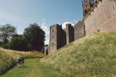 Rear view of people walking on field at arundel castle