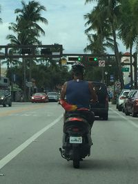 Rear view of man riding motorcycle on city street
