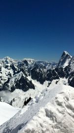 Scenic view of snow covered mountains against blue sky