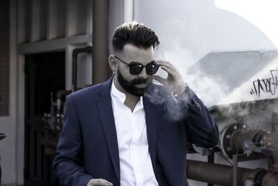 Portrait of young man wearing sunglasses standing outdoors
