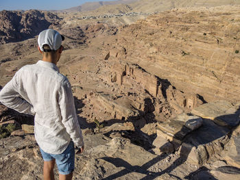 Rear view of man standing on rocky mountain