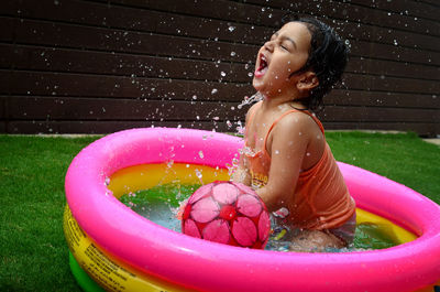 Happy girl playing in swimming pool in yard