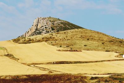 Scenic view of hill against cloudy sky