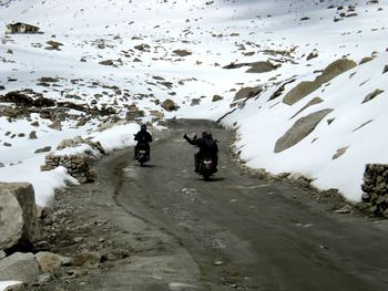 Friends riding motorbikes on road amidst snow covered mountains