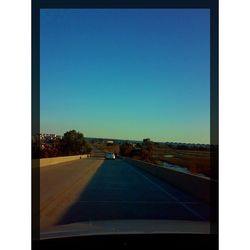 Empty road against clear blue sky